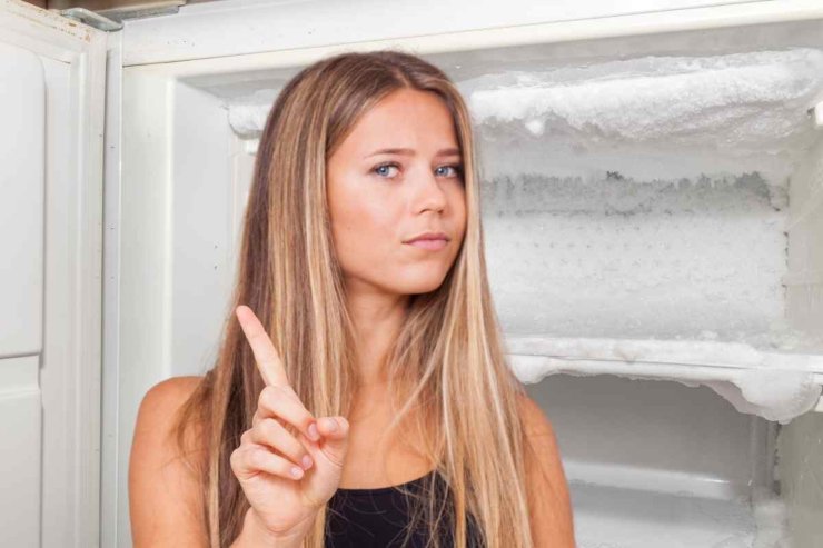 Frigo con ghiaccio e ragazza fa no con il dito