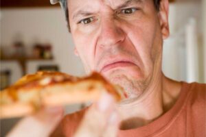 uomo disgustato da pizza in mano