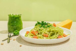 pesto in barattolo e piatto di spaghetti su tavolo