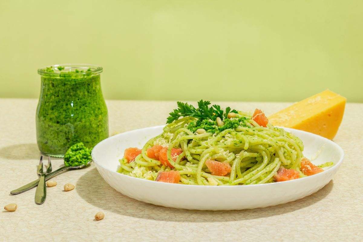 pesto in barattolo e piatto di spaghetti su tavolo