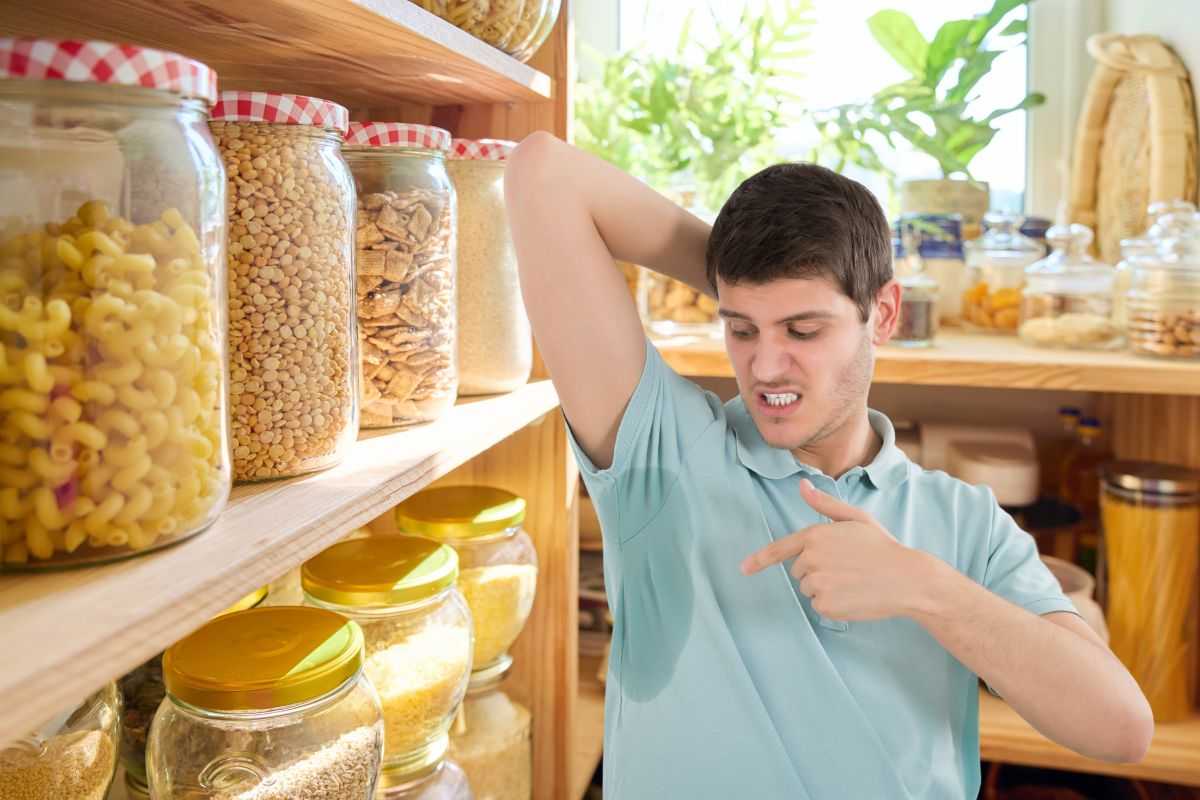 dispensa e uomo che mostra ascella sudata