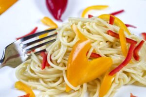 piatto di spaghetti con peperoni gialli e rossi