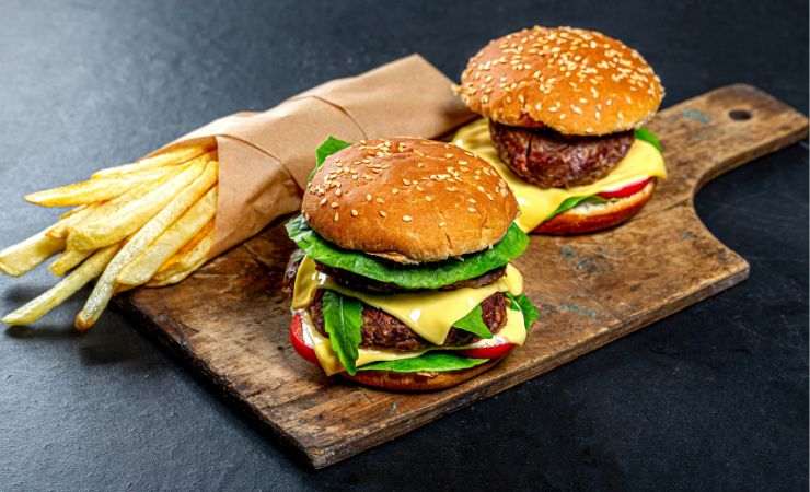 panini fast food su tagliere di legno e porzione di patatine fritte