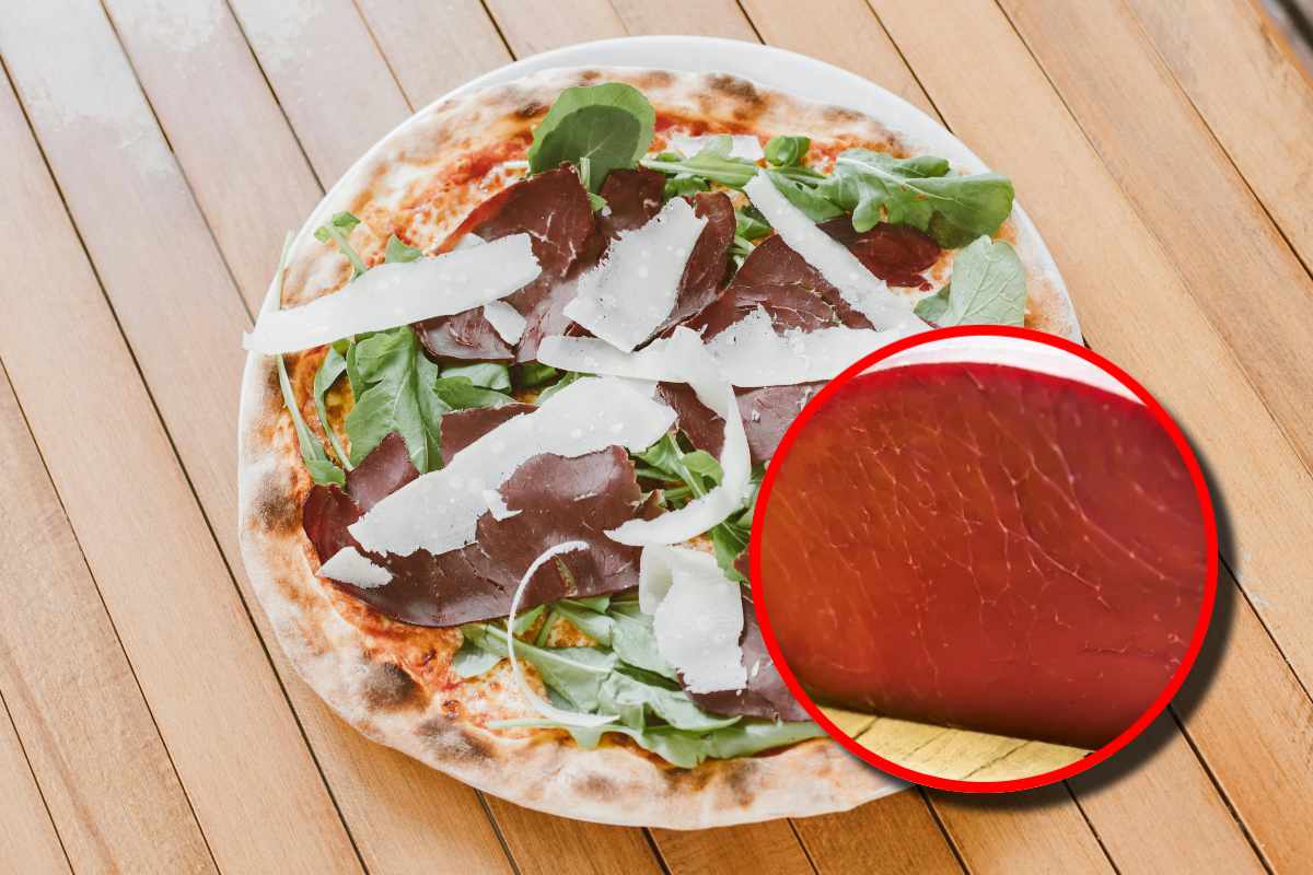 Una pizza con grana, rucola e bresaola, e in evidenza una bresaola intera