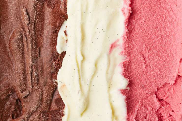 Primo piano vaschetta gelato con fragola, vaniglia e cioccolato