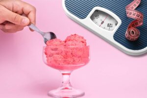 Persona che mette il cucchiaio su una coppa di gelato alla fragola e bilancia con metro sullo sfondo