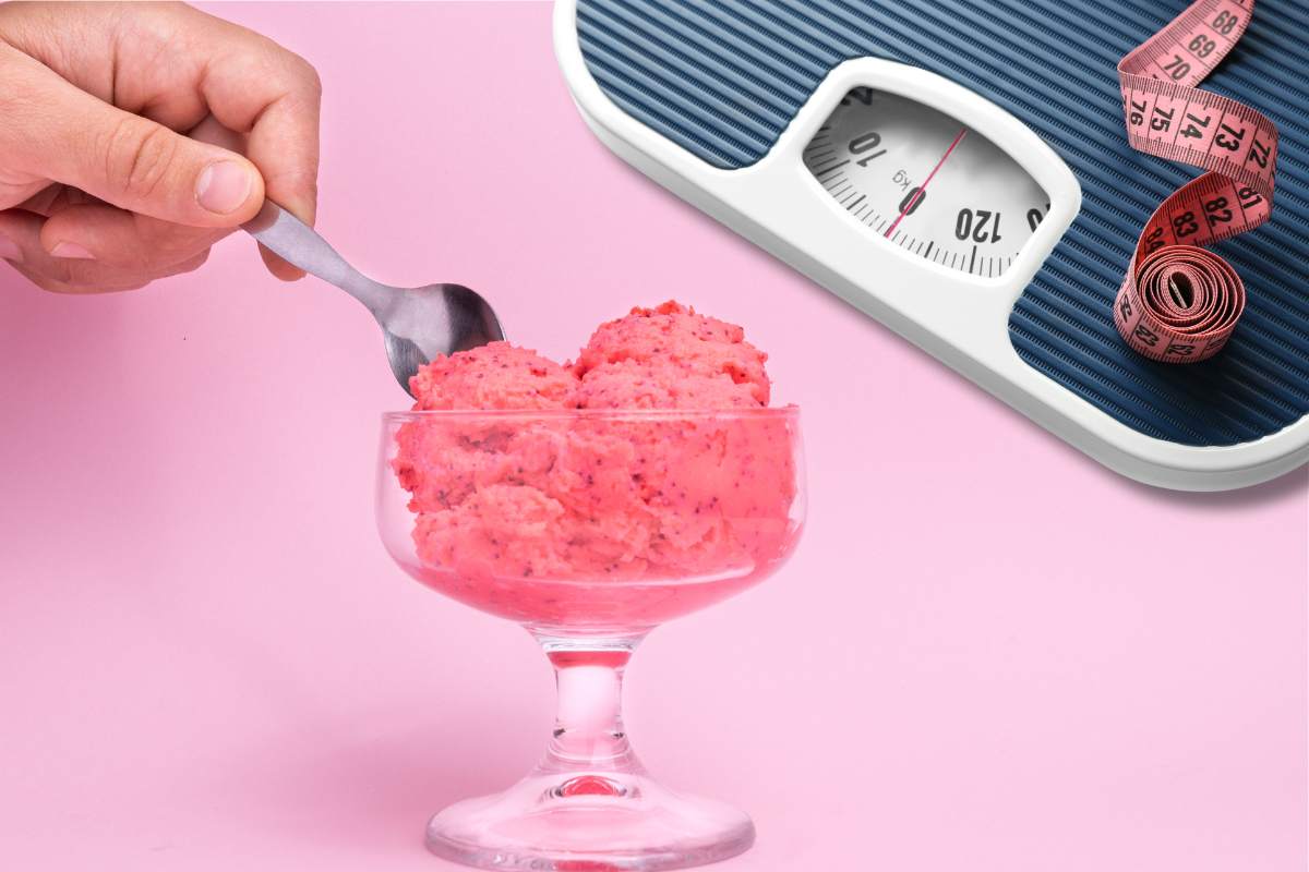 Persona che mette il cucchiaio su una coppa di gelato alla fragola e bilancia con metro sullo sfondo