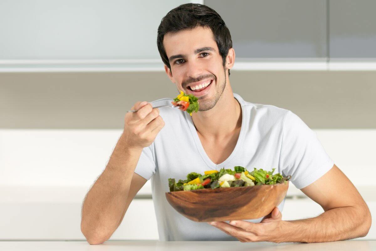 Ragazzo mangia insalata da bowl in legno