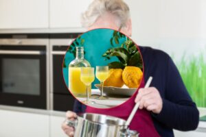 persona matura in cucina e limoncello in primo piano