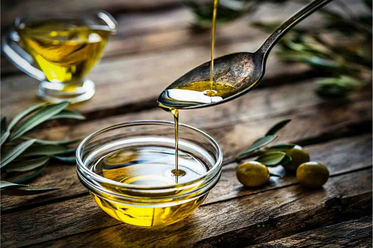 Ciotola con olio d'oliva, cucchiaio, olive