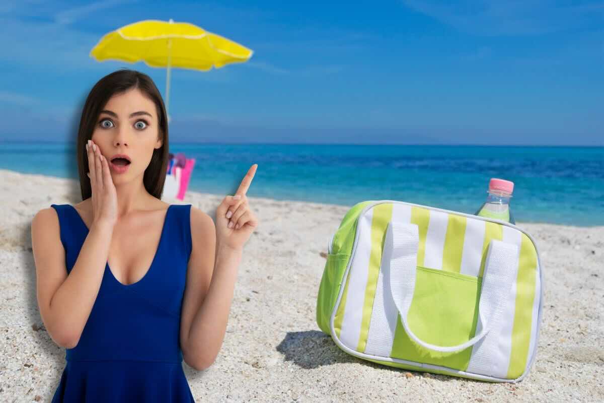 Ragazza stupita con dito alzato, borsa frigo in spiaggia, ombrellone