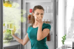 donna che si tappa il naso per la puzza che esce dal frigo