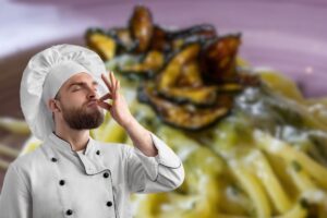 spaghetti alla nerano nel piatto e chef che butta bacio