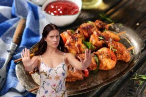 donna che dice no e piatto di spiedini di carne