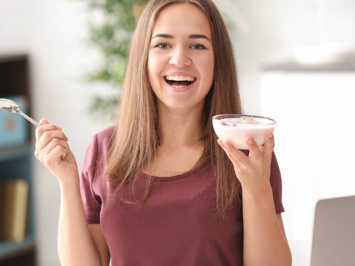 donna sorridente con yogurt in mano 