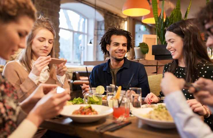 amici con telefono a tavola